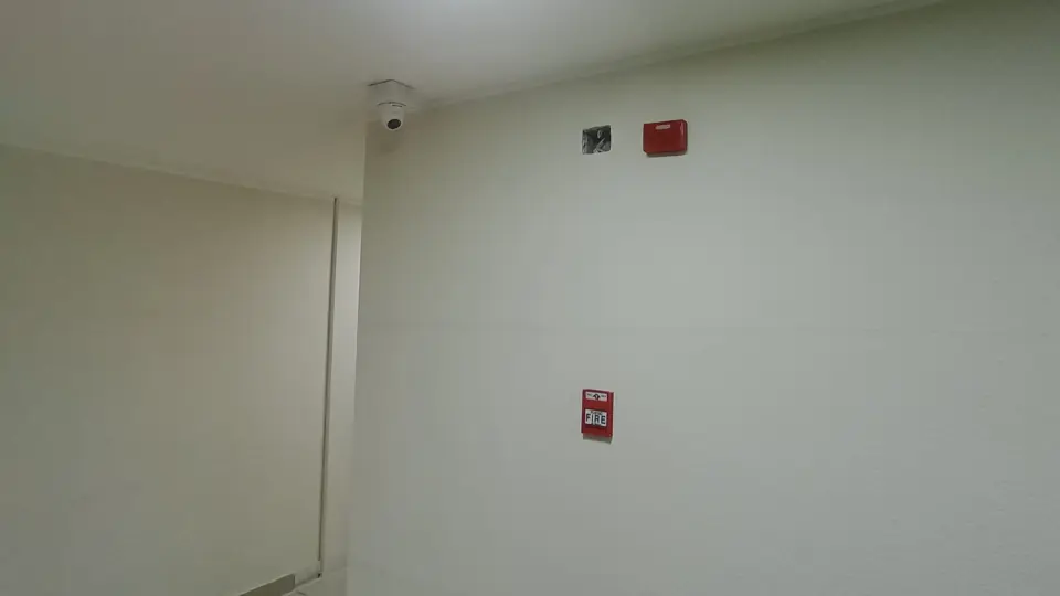 Sistema de seguridad con cámara de vigilancia, palanca de accionamiento manual y sirena de alarma contra incendios.